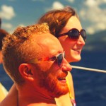 marion et geoffrey, un jeune couple qui vit en martinique, se trouvent sur le pont d'un voilier et sourient face à la mer des caraïbes