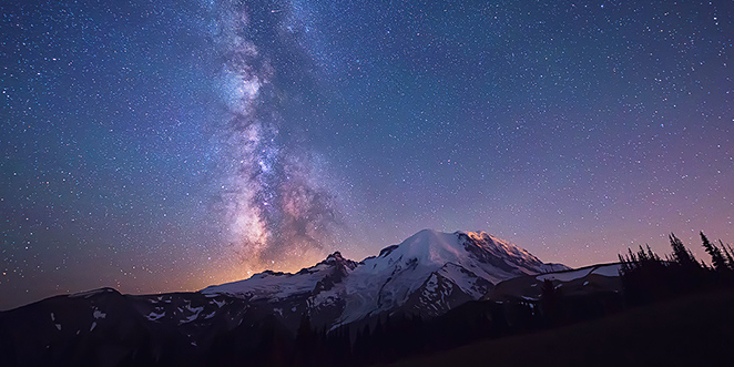 une montagne et un glacier sont photographiés de nuit en pose longue sous une véritable pluie d'étoiles et de galaxies