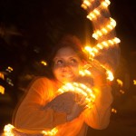 sharon entoure un palmier avec les bras, celui ci est recouvert d'une guirlande lumineuse et la photo est floue 